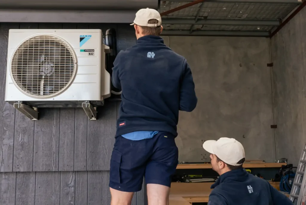 Technicians performing maintenance on an air conditioner in Perth, highlighting signs of needed service.