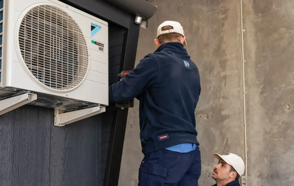 Technicians servicing an air conditioning unit, highlighting benefits of regular air conditioning servicing in Perth.
