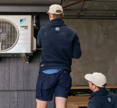 Technicians performing maintenance on an air conditioner in Perth, highlighting signs of needed service.