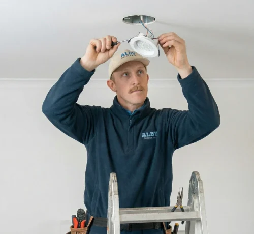 Electrician changing an LED downlight, showcasing electrical services in Perth.