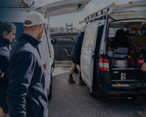 Electricians unloading tools from service vans for a job